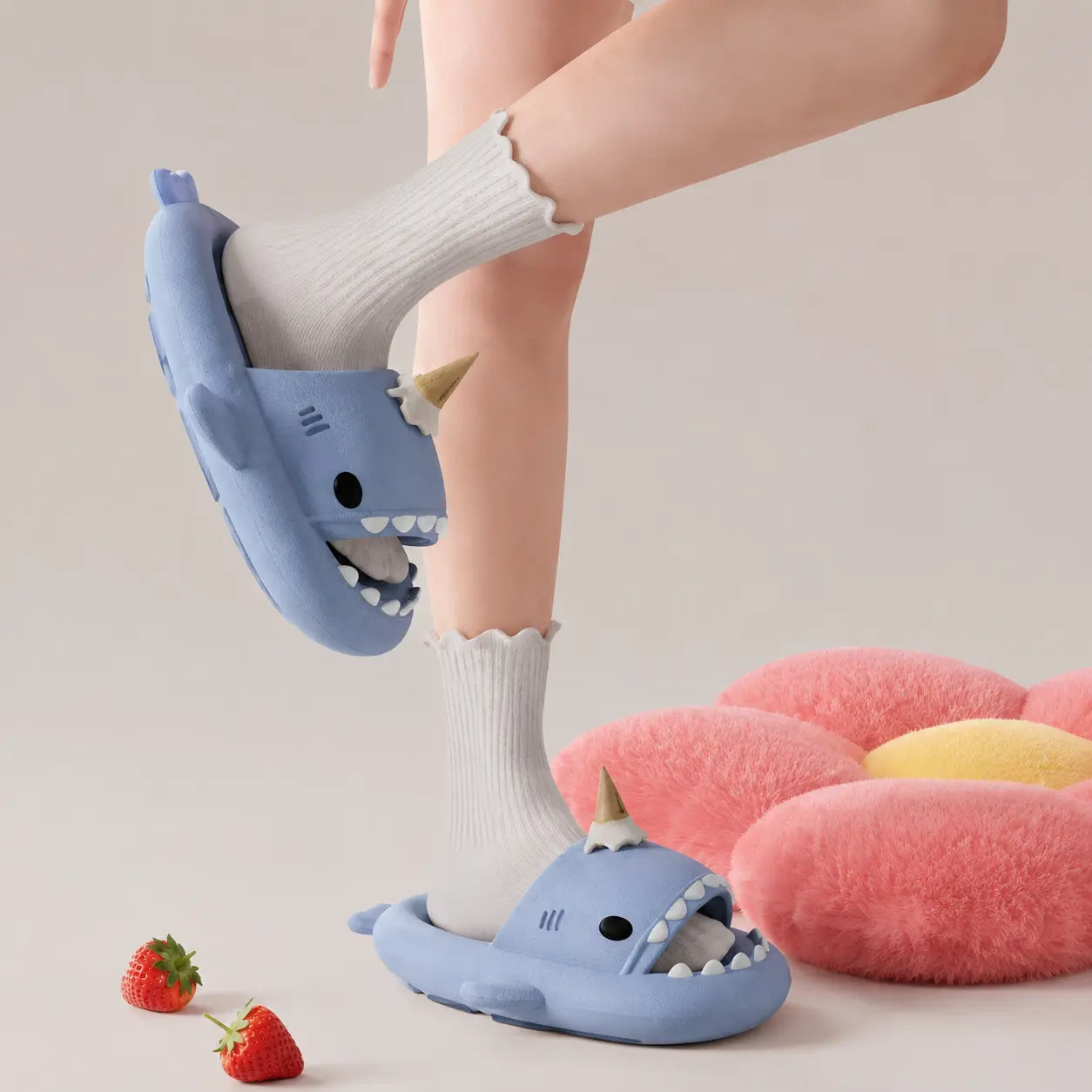 Person wearing blue shark-shaped slippers with white socks on a neutral background