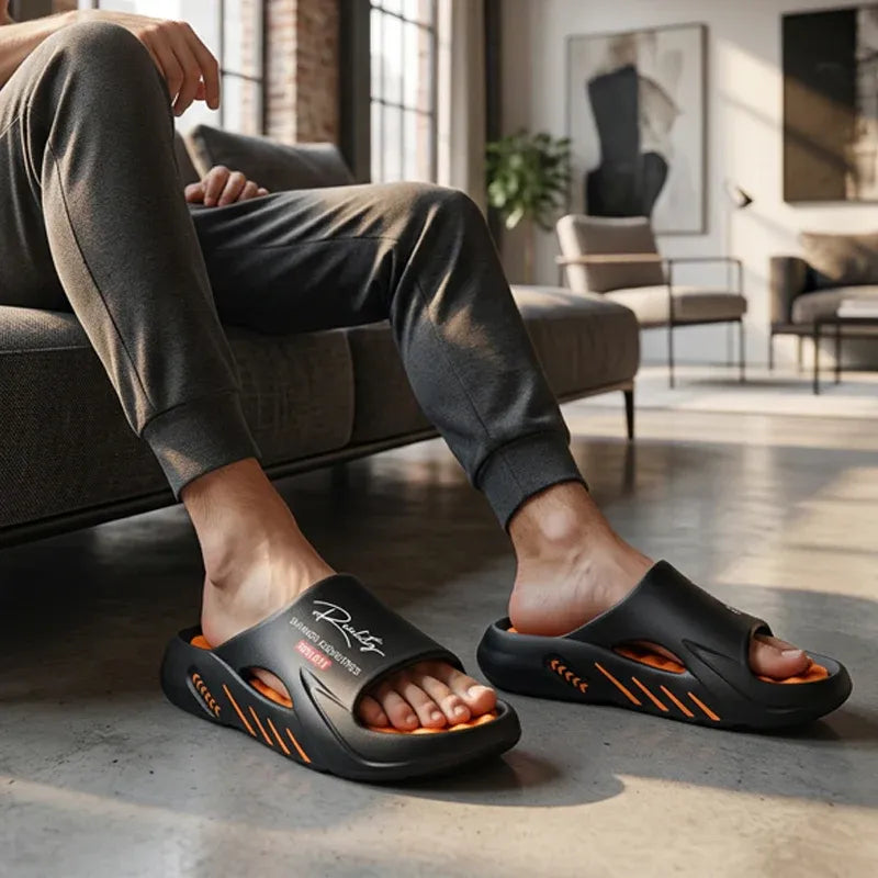 Person wearing black slides with orange accents in a modern living room.