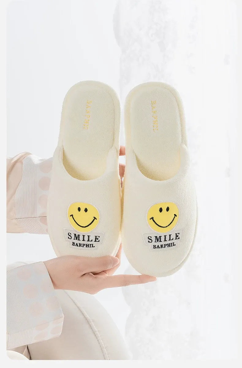 White slippers with smiley face design held by a person on a white background