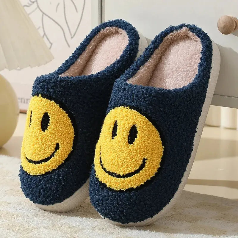 Pair of navy blue slippers with yellow smiley face design on a light background