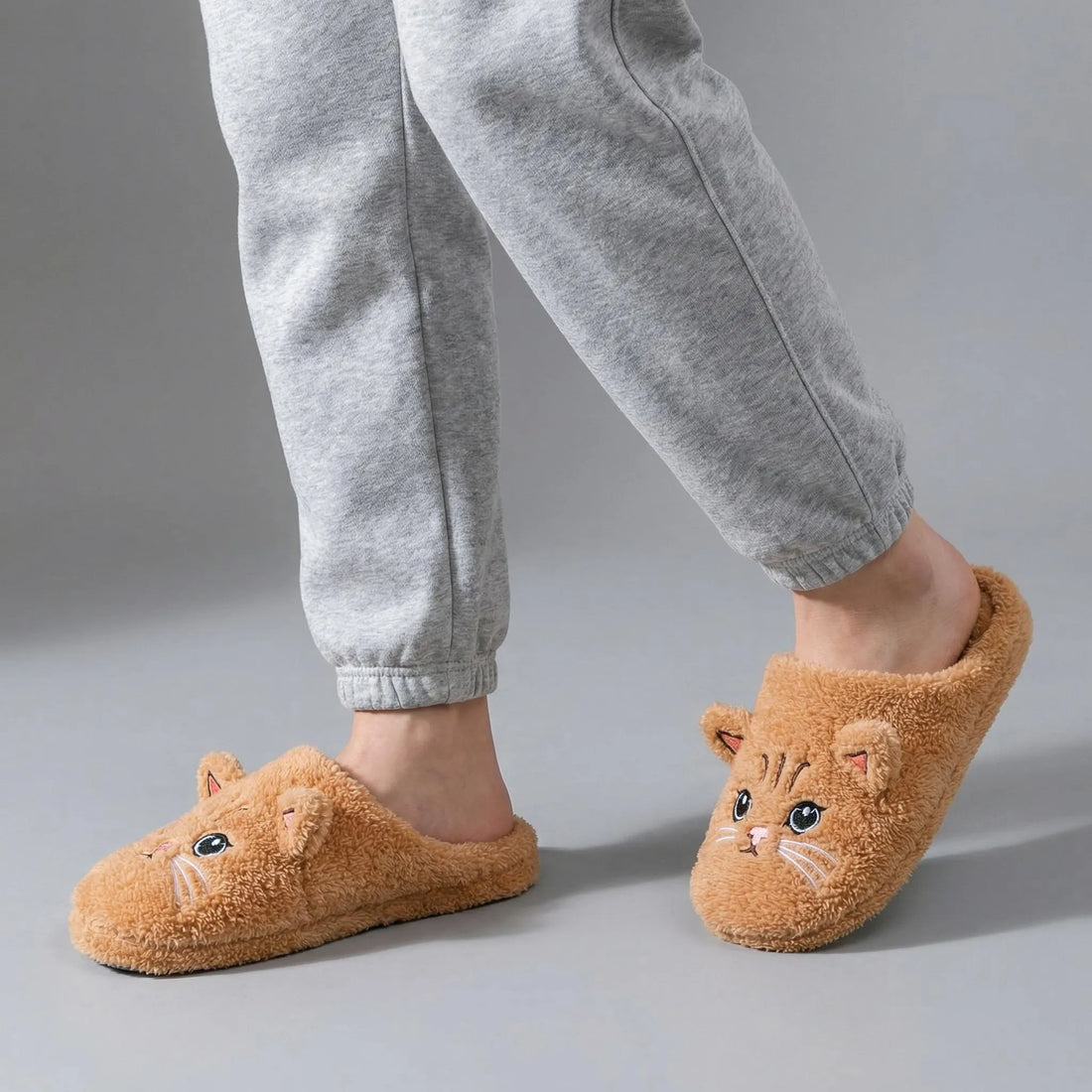 Black cat-shaped slippers worn on a beige carpet