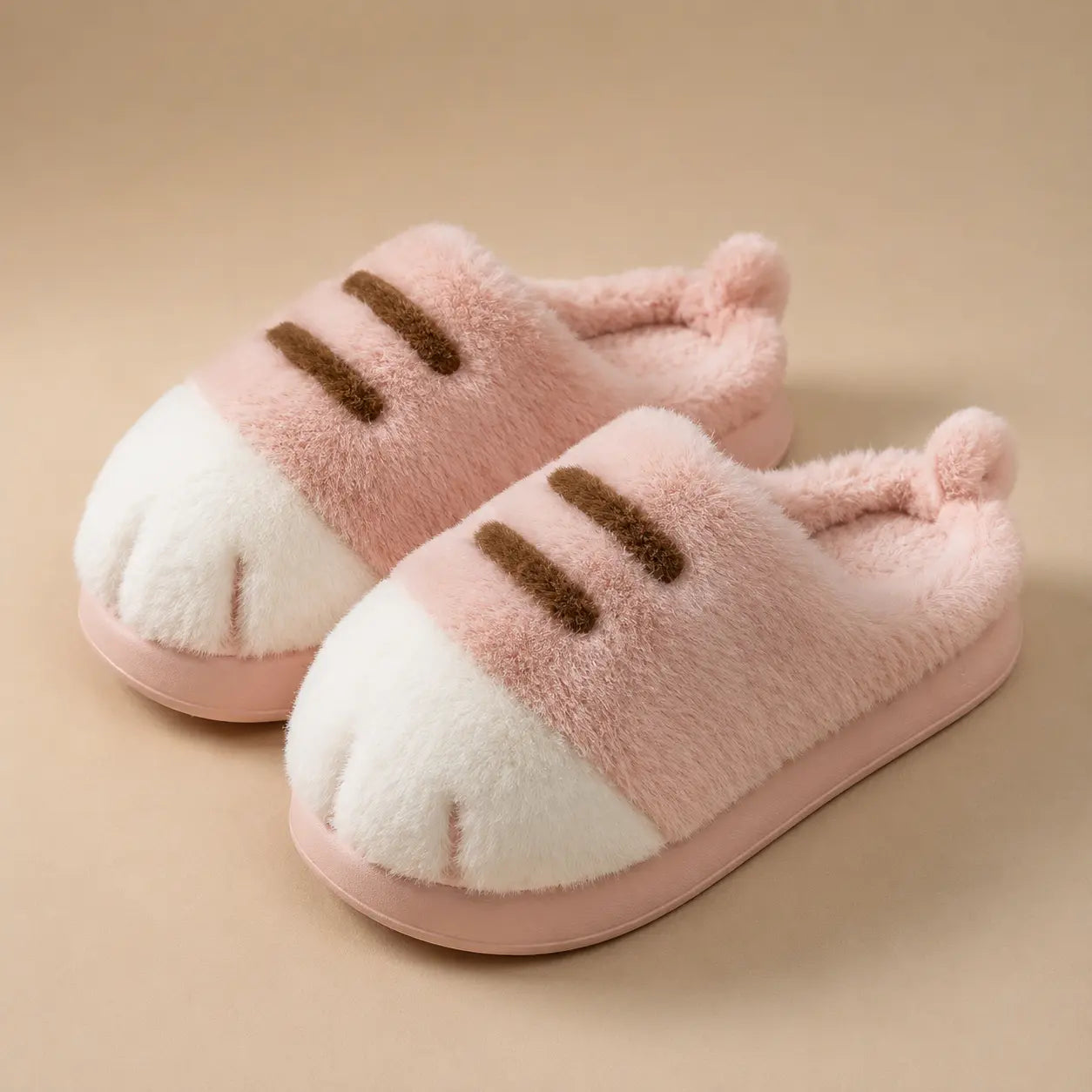 Pair of pink slippers with cat paw design on a beige background