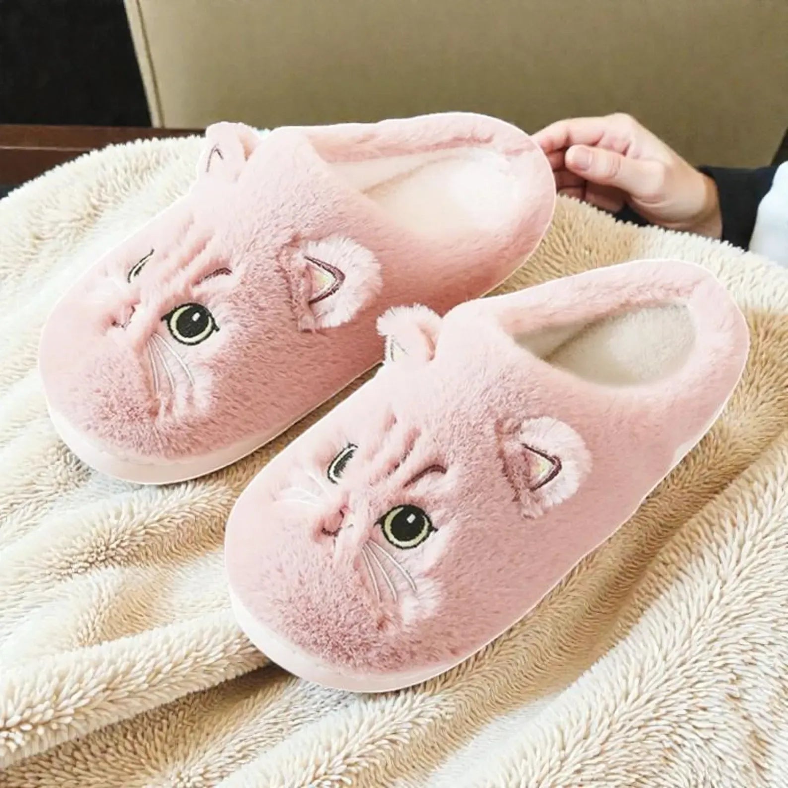 Pink cat-shaped slippers on a fluffy beige surface