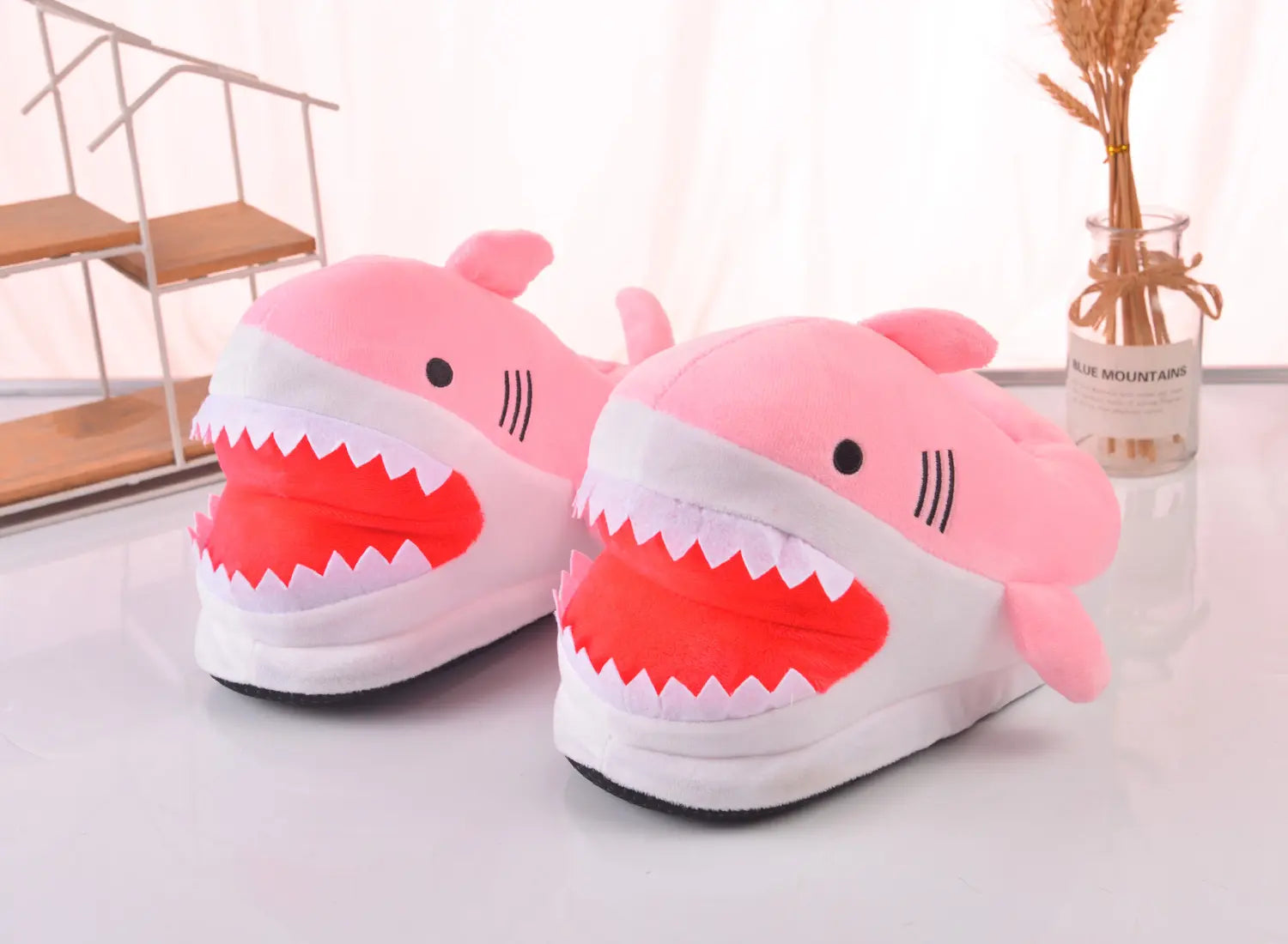 Pink shark-shaped slippers on a light surface with a blurred background
