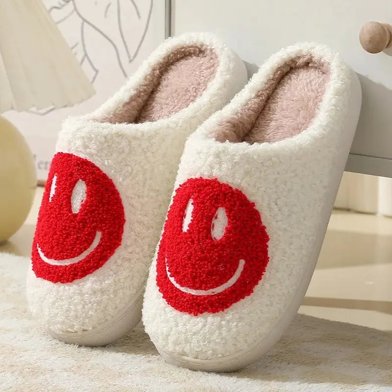 White slippers with red smiley face design on a soft surface