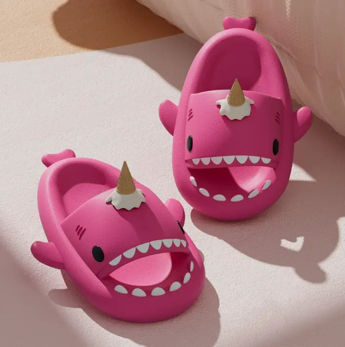 Pink shark-shaped sandals with unicorn horn on a light surface