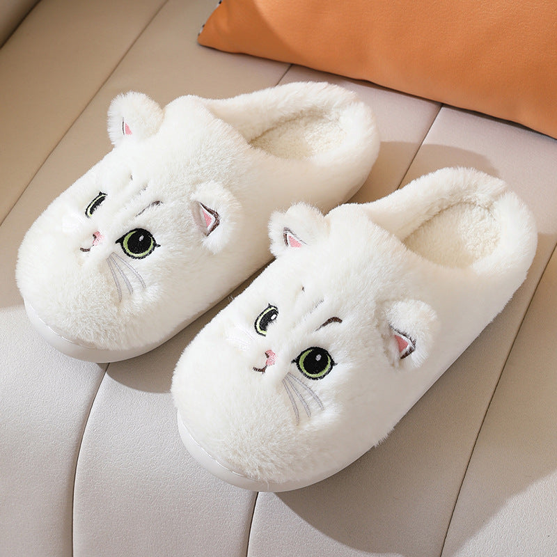 Pair of white cat-shaped slippers on a light-colored surface.