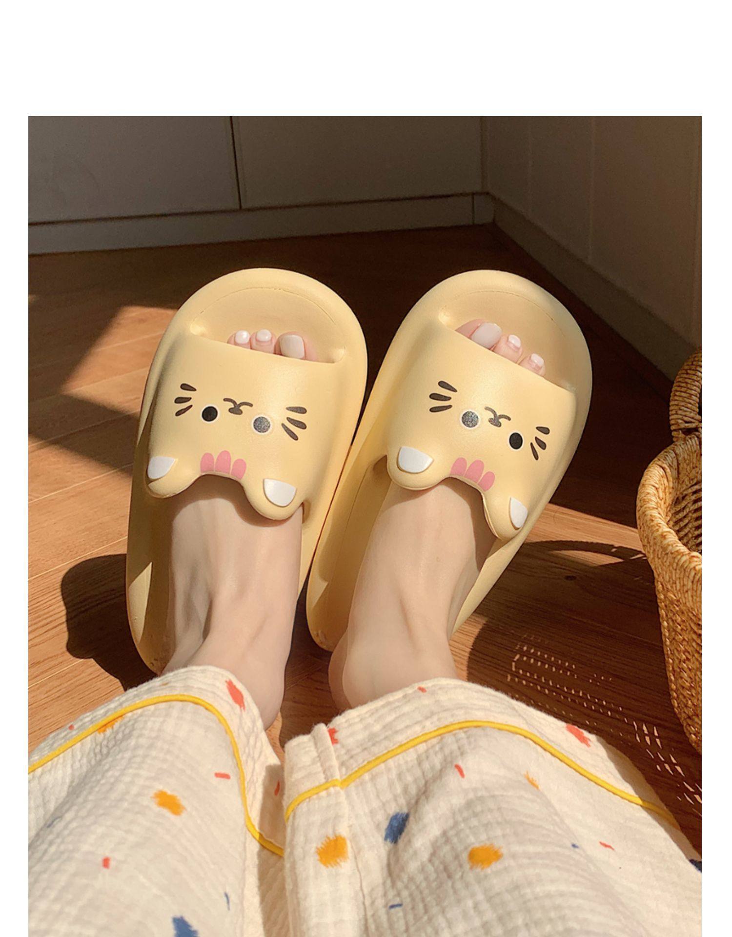 Yellow cat-themed slippers worn indoors on a wooden floor.