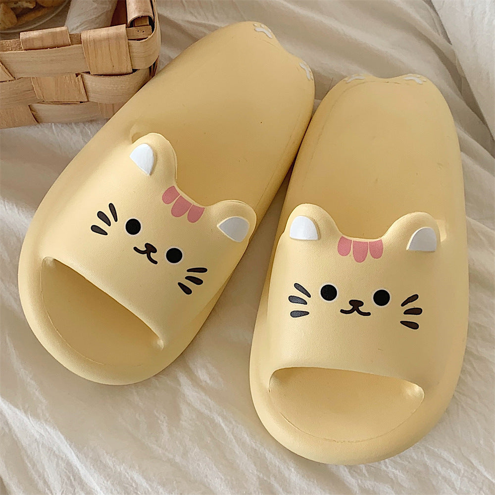 Pair of yellow cat-shaped slippers on a light fabric background
