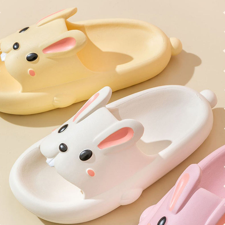 Two pairs of rabbit slippers, one beige and one pink, on a light background.