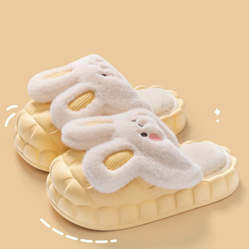 Pair of white bunny slippers with yellow interior on a beige background