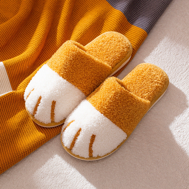 Pair of orange slippers with white soles on a textured surface