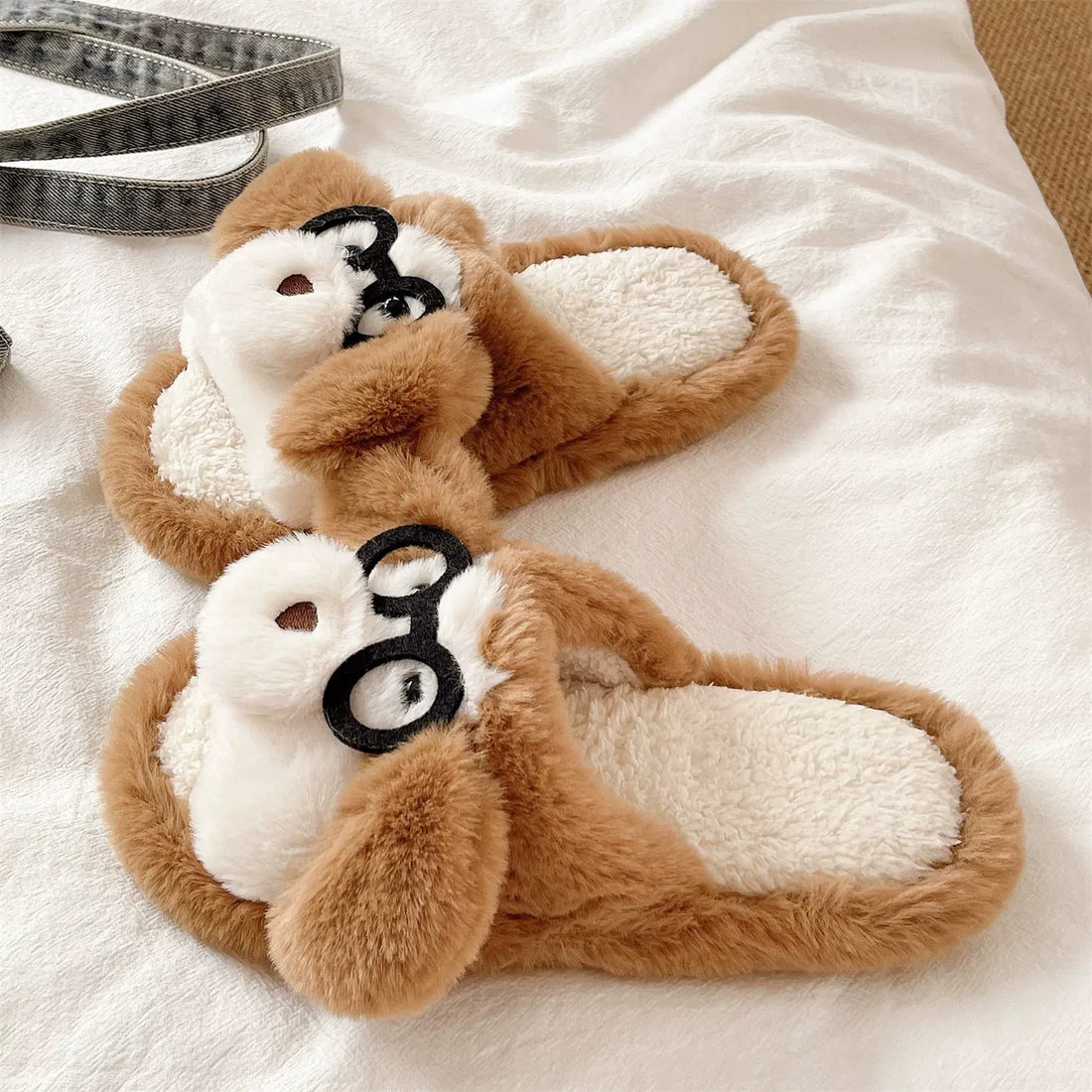Pair of brown and white slippers with a dog design on a white surface