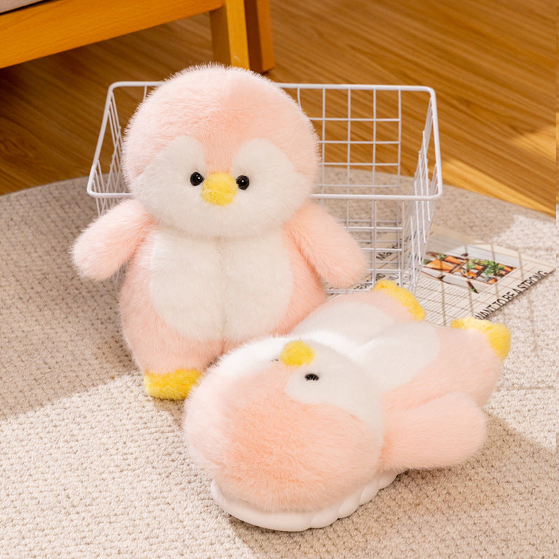 pink plush penguin slippers on a carpeted floor with a basket in the background.