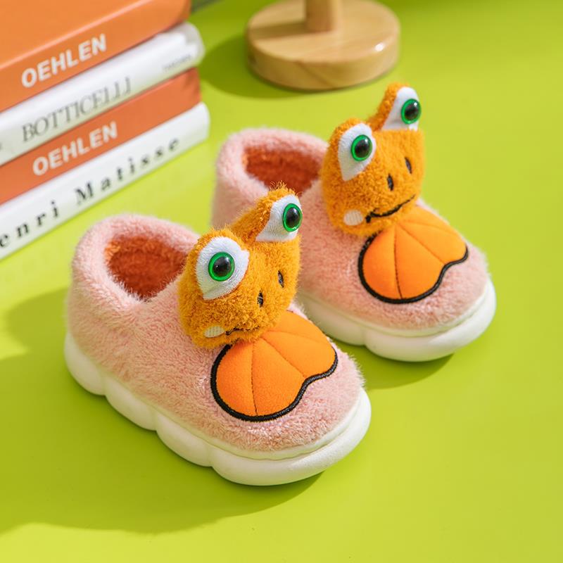 Pair of pink children's shoes with cartoon face design on a green surface