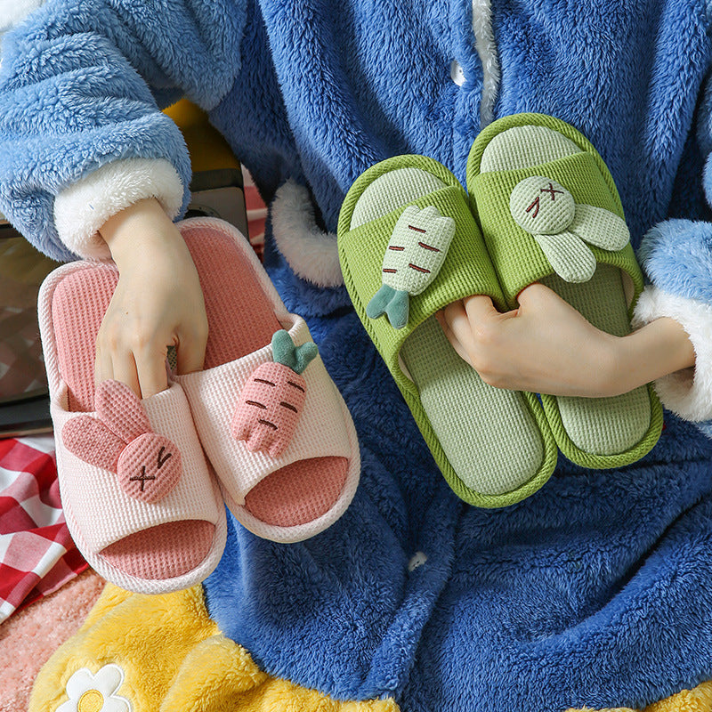 Person holding green and pink bunny slippers in a cozy setting