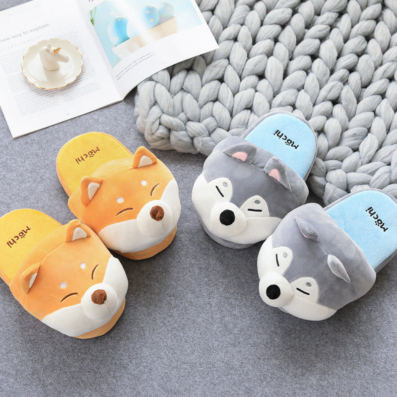 Pair of Novelty animal themed slippers on a textured surface with a blanket in the background.