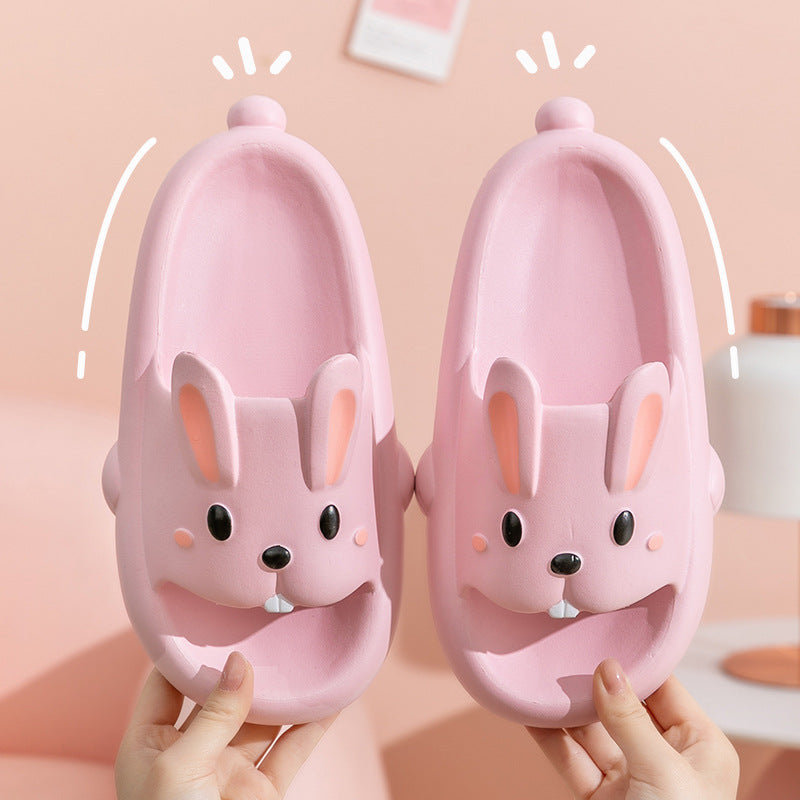 Pink rabbit-shaped slippers held by hands against a pink background