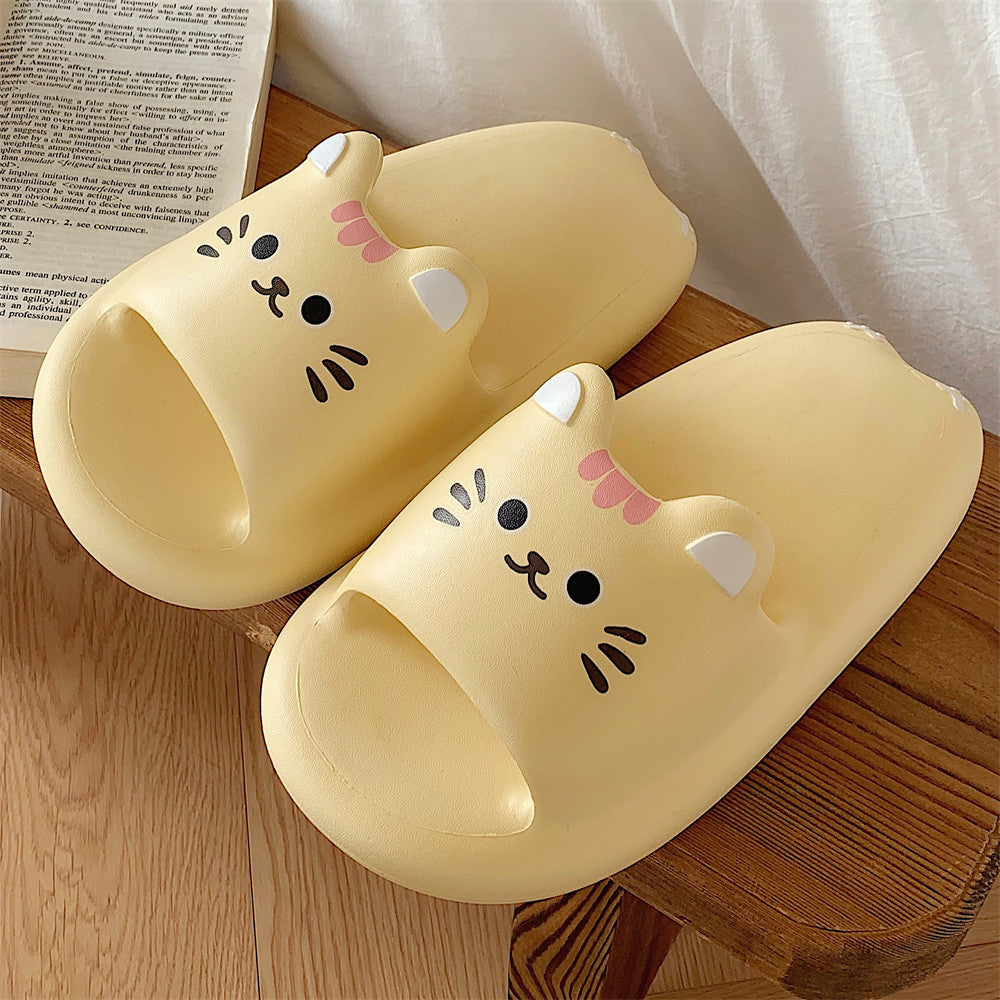 Pair of yellow cat-shaped slippers on a light fabric background