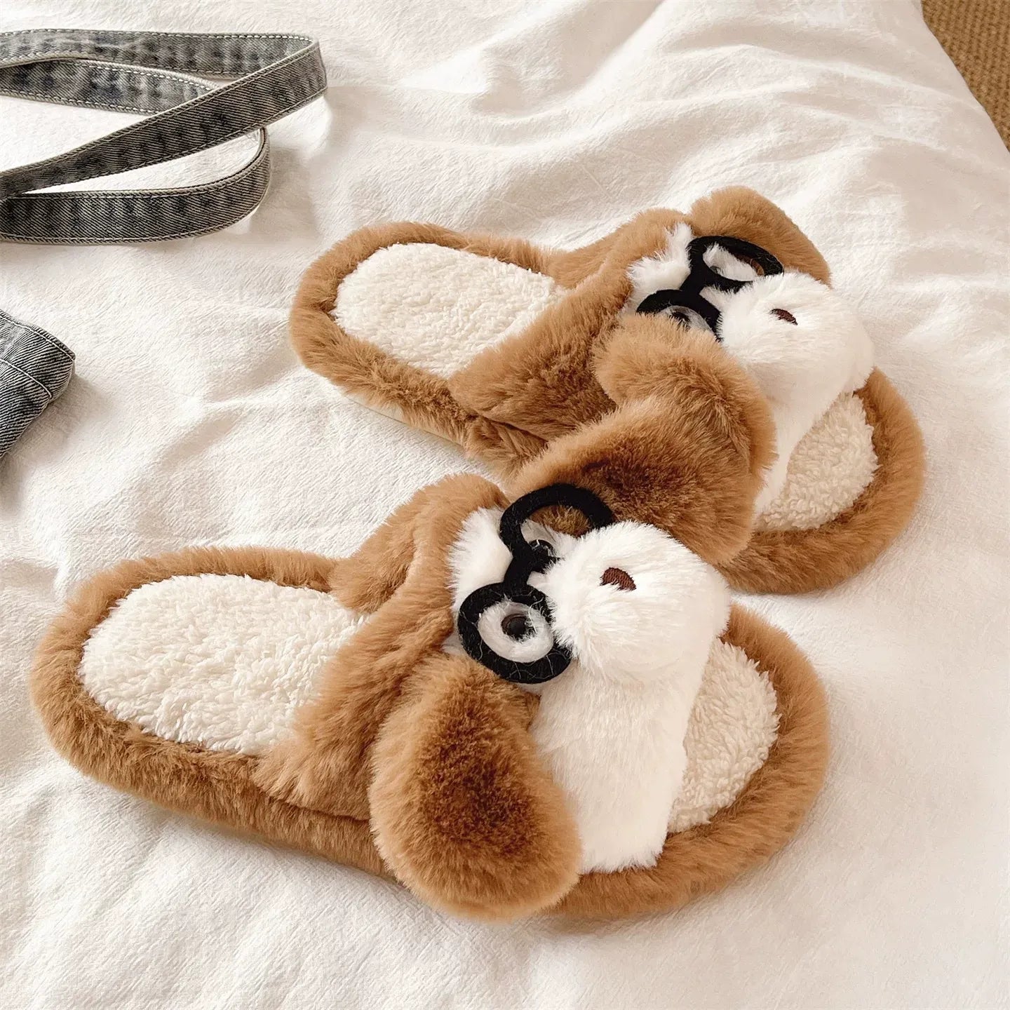 Pair of brown and white dog-shaped slippers on a white surface.