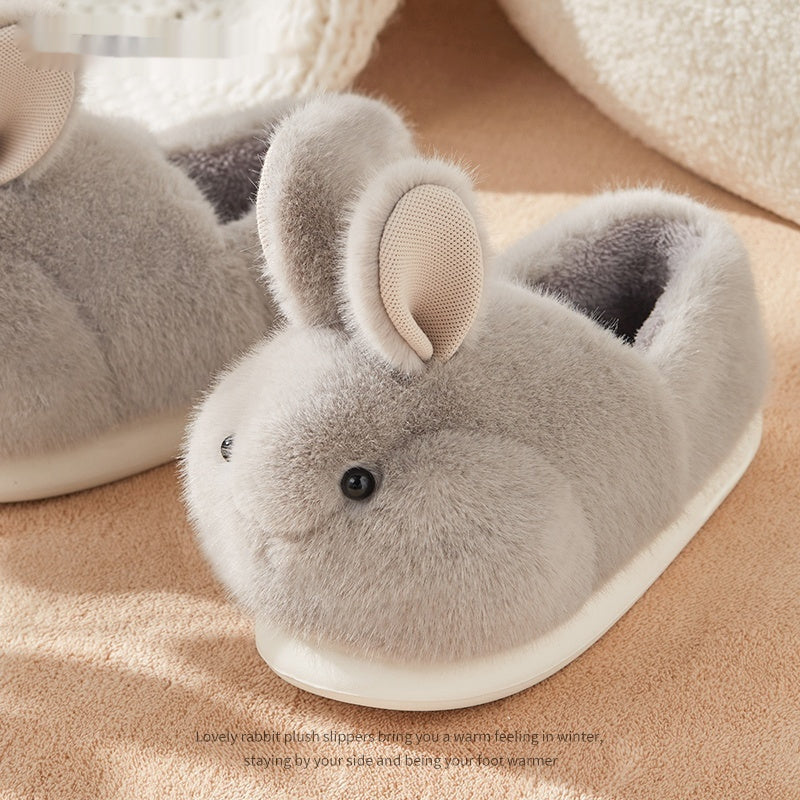 Gray plush bunny slippers on a beige surface