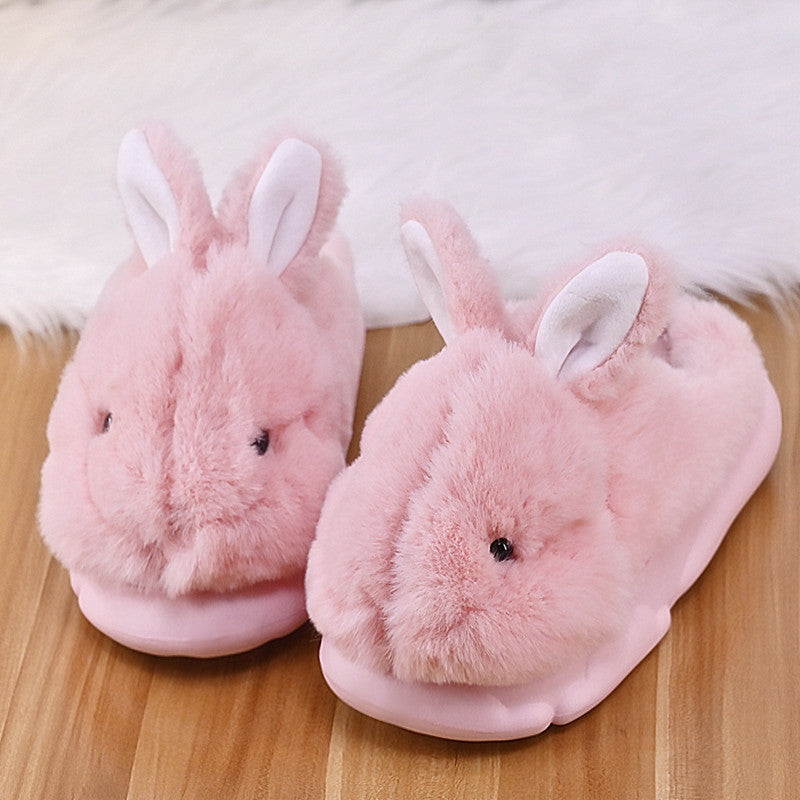 Pair of pink Rabbit slippers on a wooden floor.