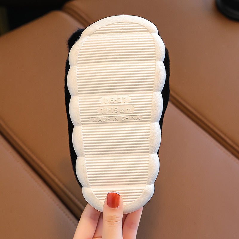White slippers with textured sole held by a hand on a brown surface