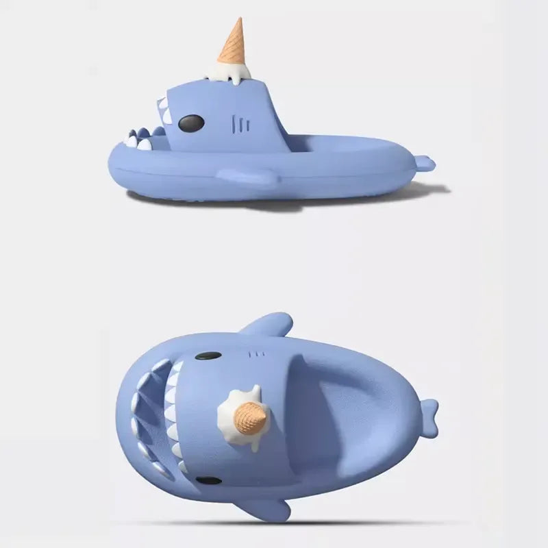 Two blue shark-shaped bath toys with ice cream cone and shell details on a light gray background