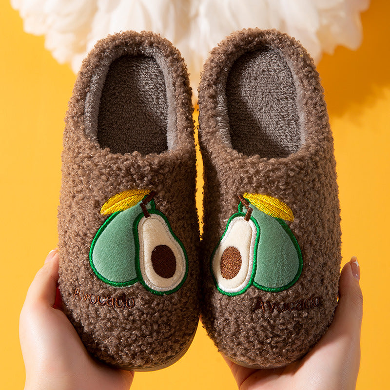 Brown slippers with avocado design held against a yellow background