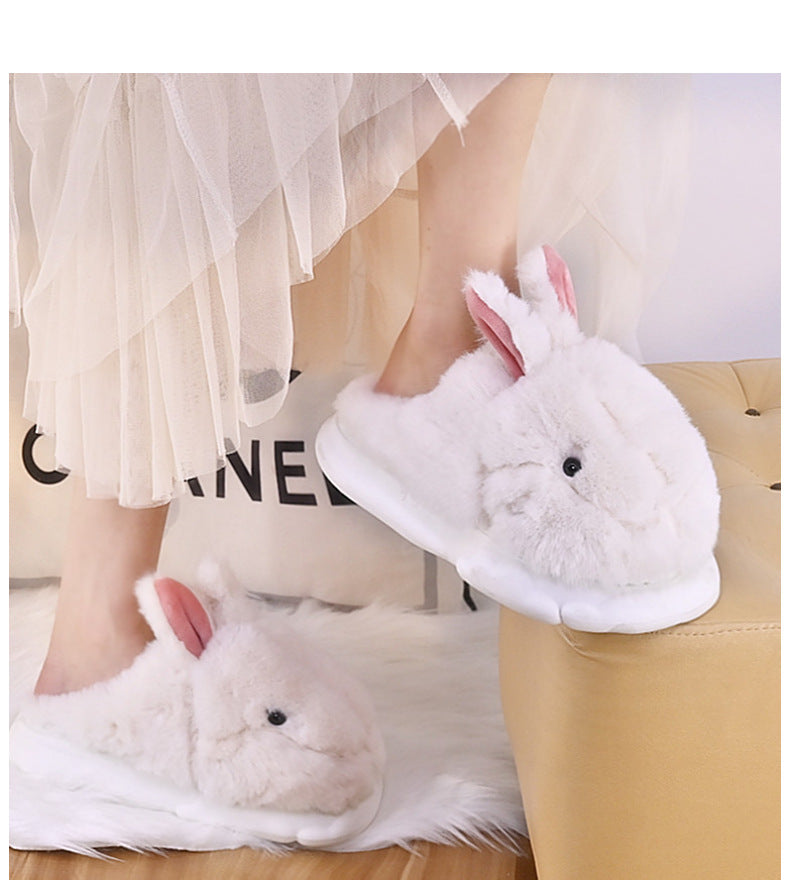 White Rabbit slippers worn by a person sitting on a beige chair.