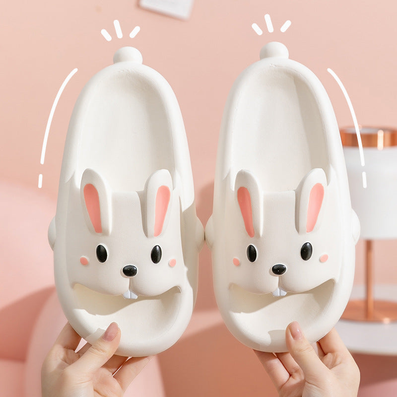 Pair of white bunny slippers held against a pink background