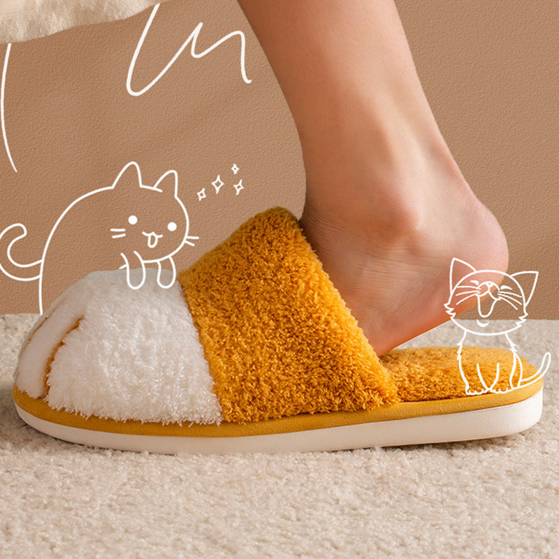 Close-up of a foot wearing a yellow and white slipper with cartoon cat illustrations on a beige background.