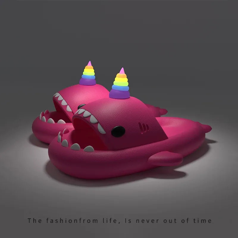 Pink shark-shaped toy with rainbow horns on a dark background
