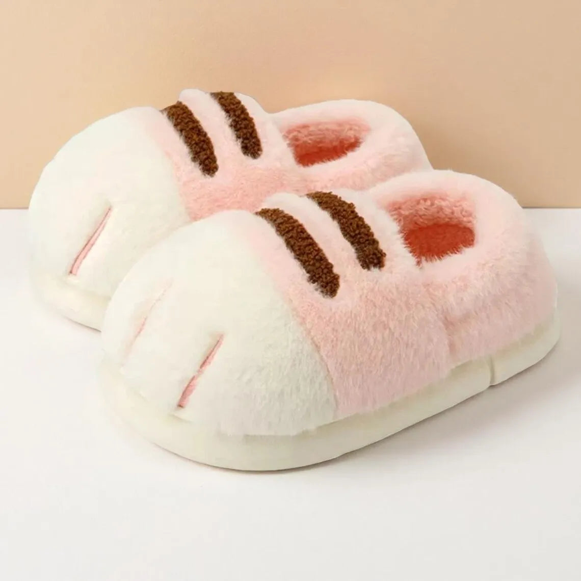 Pair of pink and white slippers with brown accents on a beige background