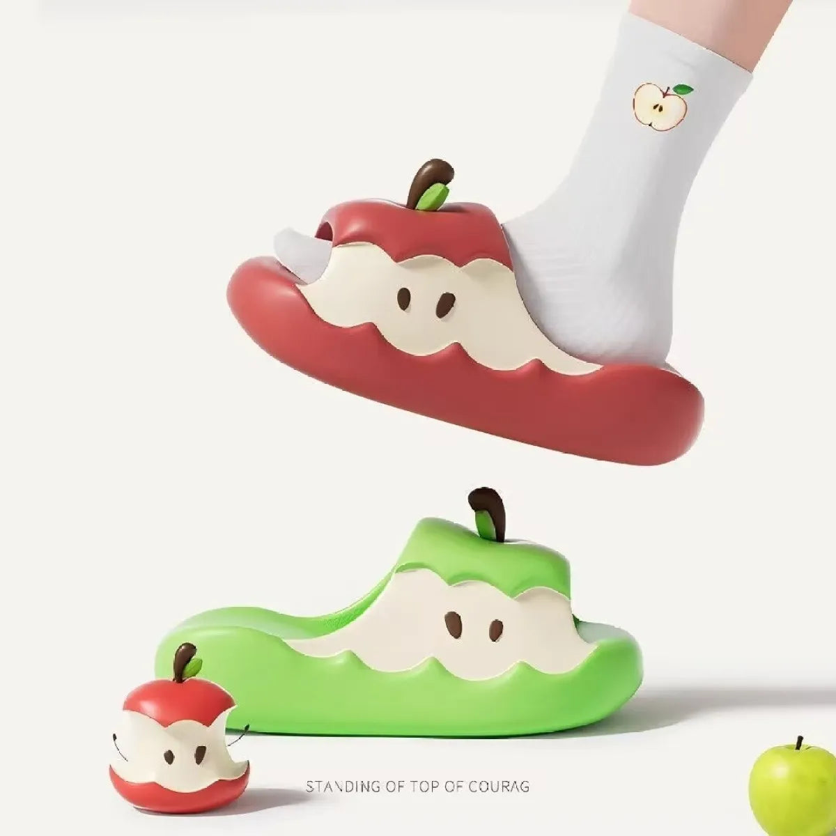 Apple-shaped slippers with a small apple toy on a white background