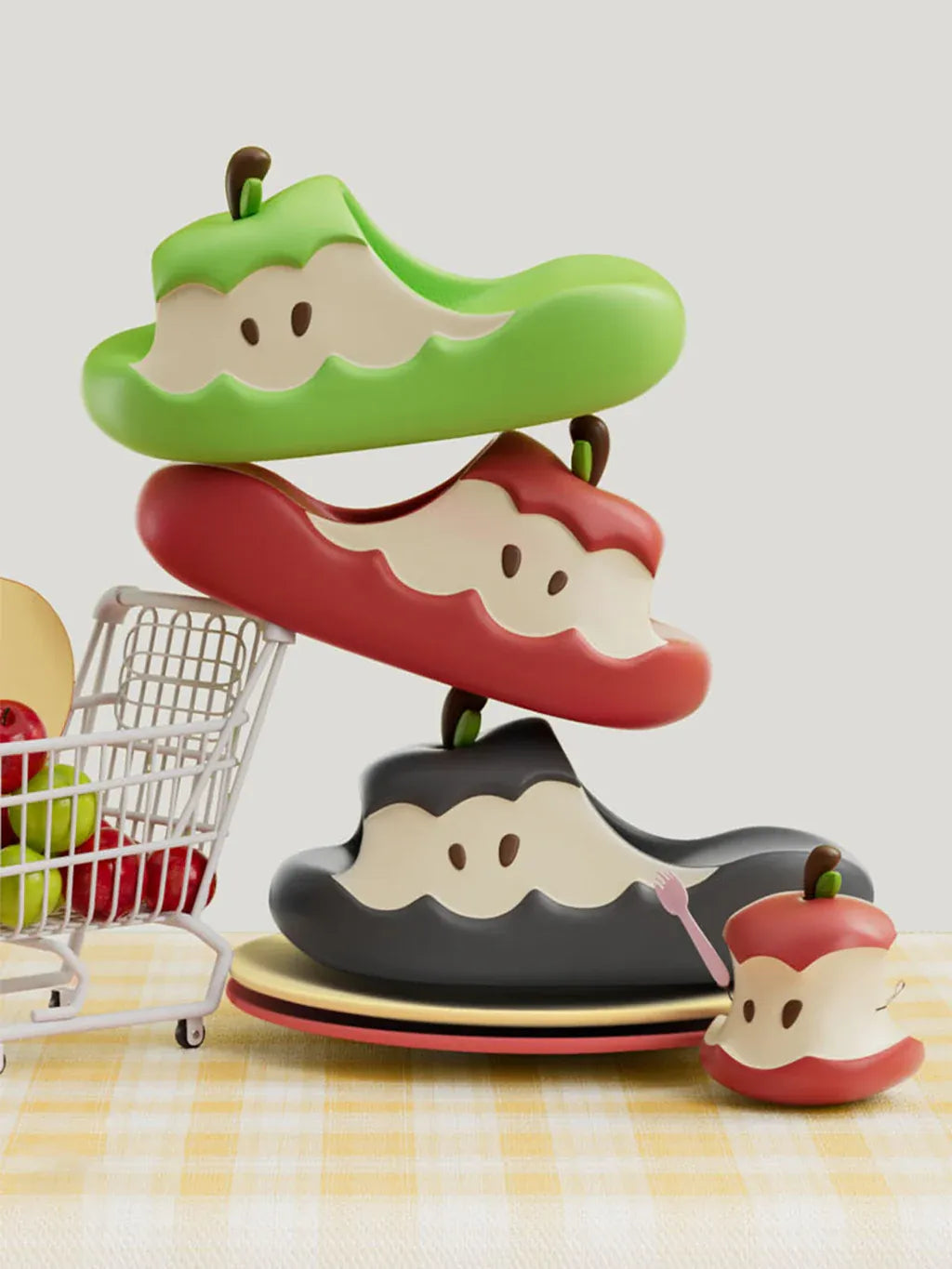 showing red, green and black apple slippers, near a small apple toy is places