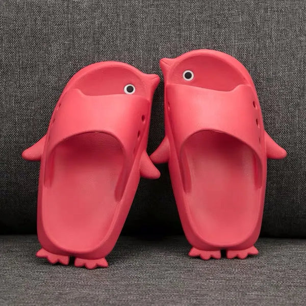 Pair of red penguin-shaped slippers on a gray textured background