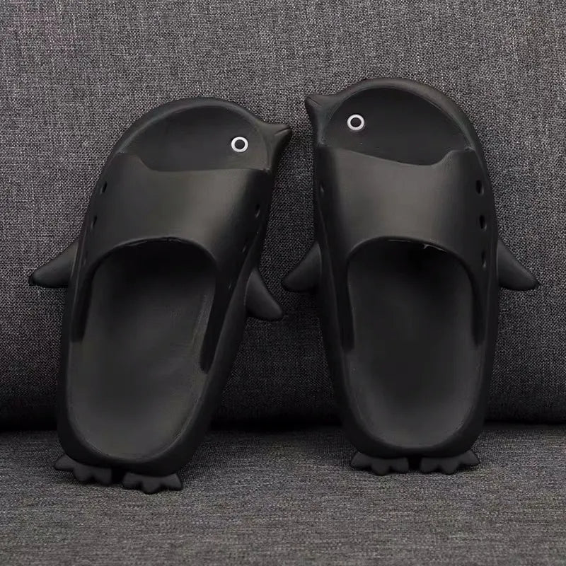 Pair of red penguin-shaped slippers on a gray textured background
