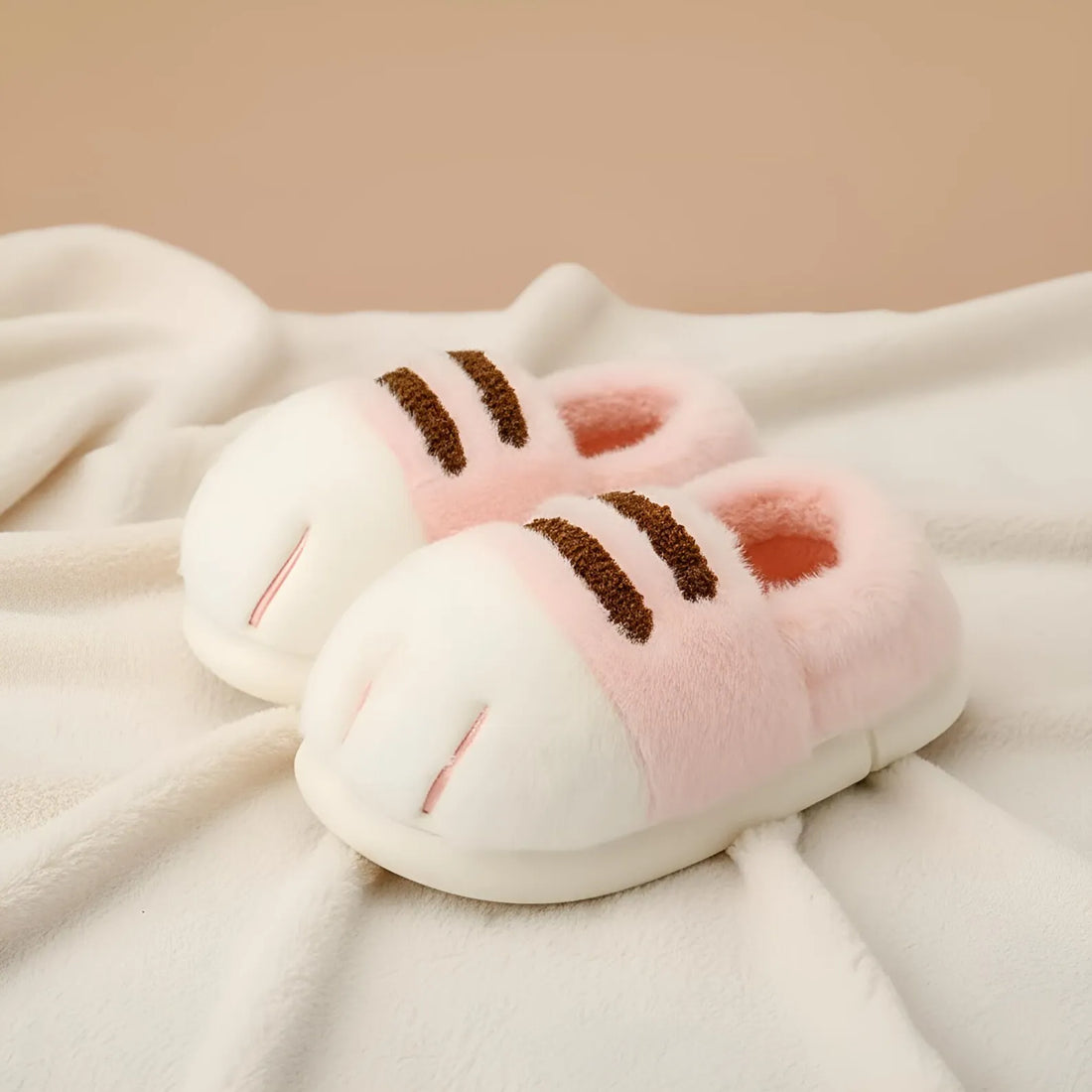 Pair of pink and white slippers with brown accents on a soft fabric background
