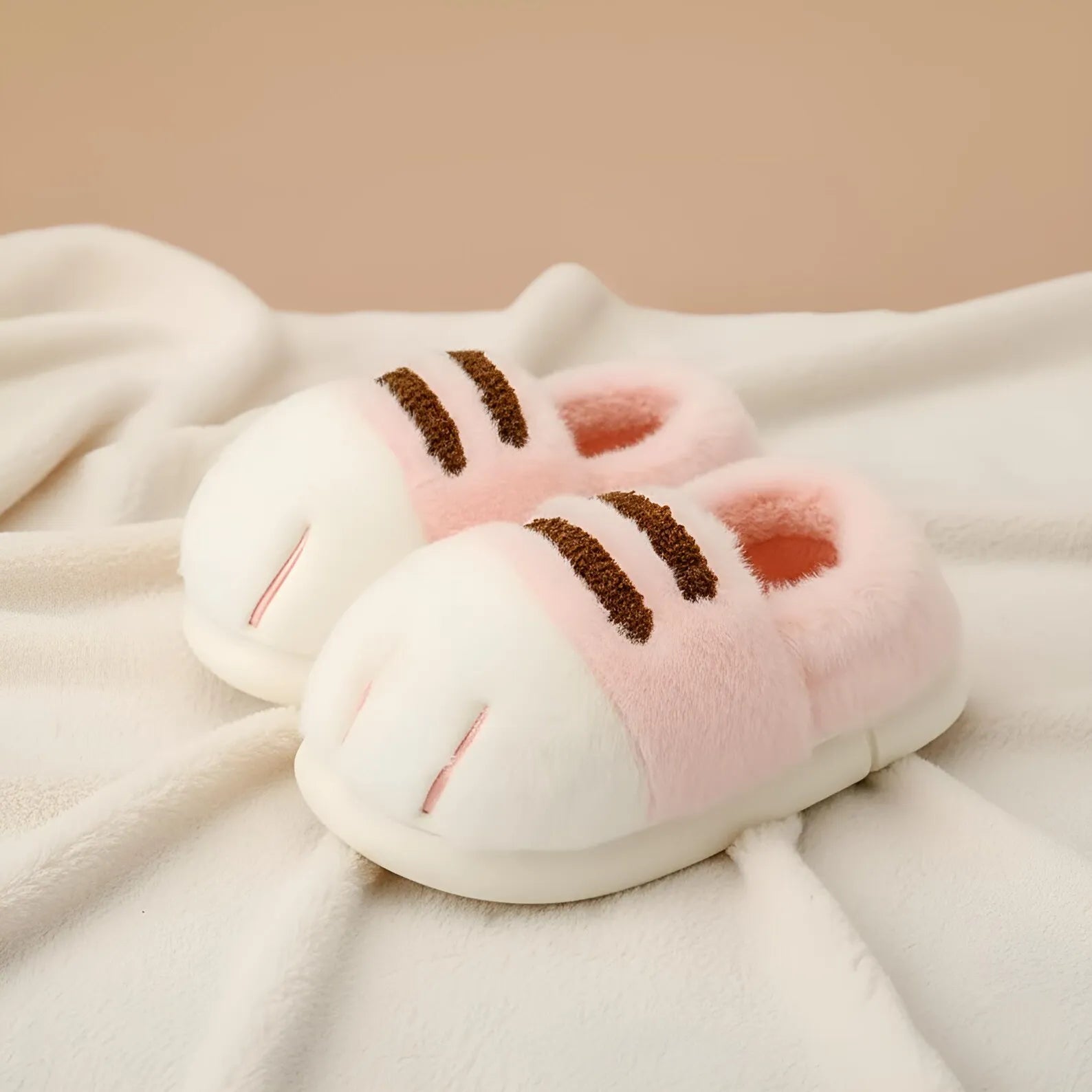 Pair of pink and white slippers with brown accents on a soft fabric background