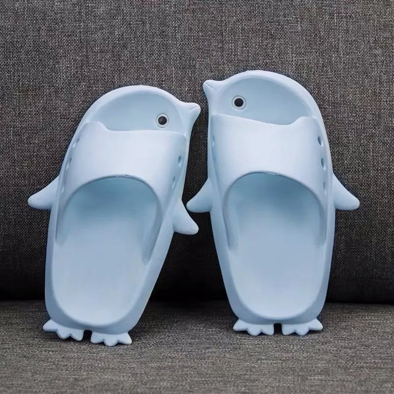 Pair of blue penguin-shaped slippers on a textured brown background
