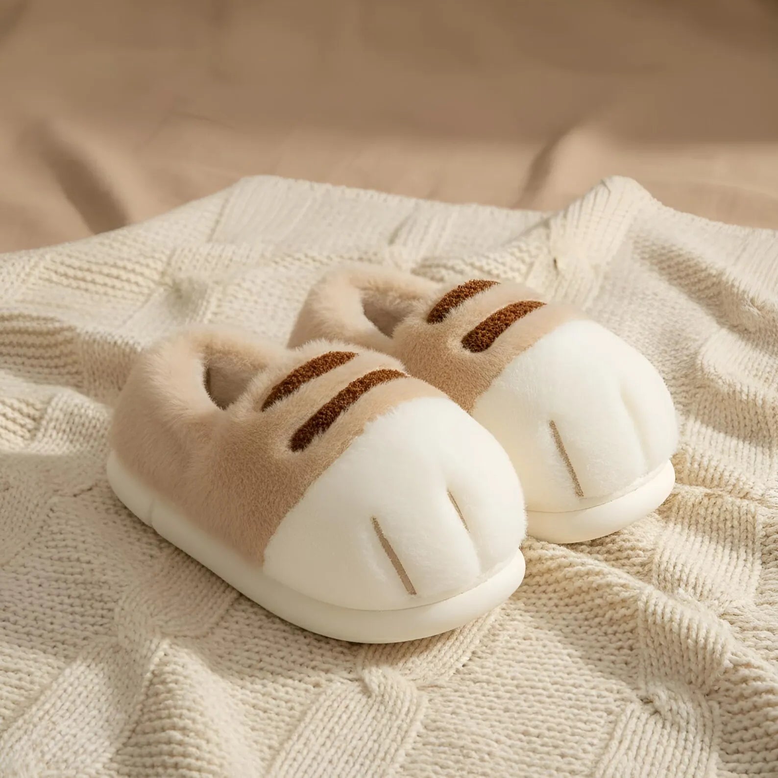 Pair of cat-shaped slippers on a textured fabric surface