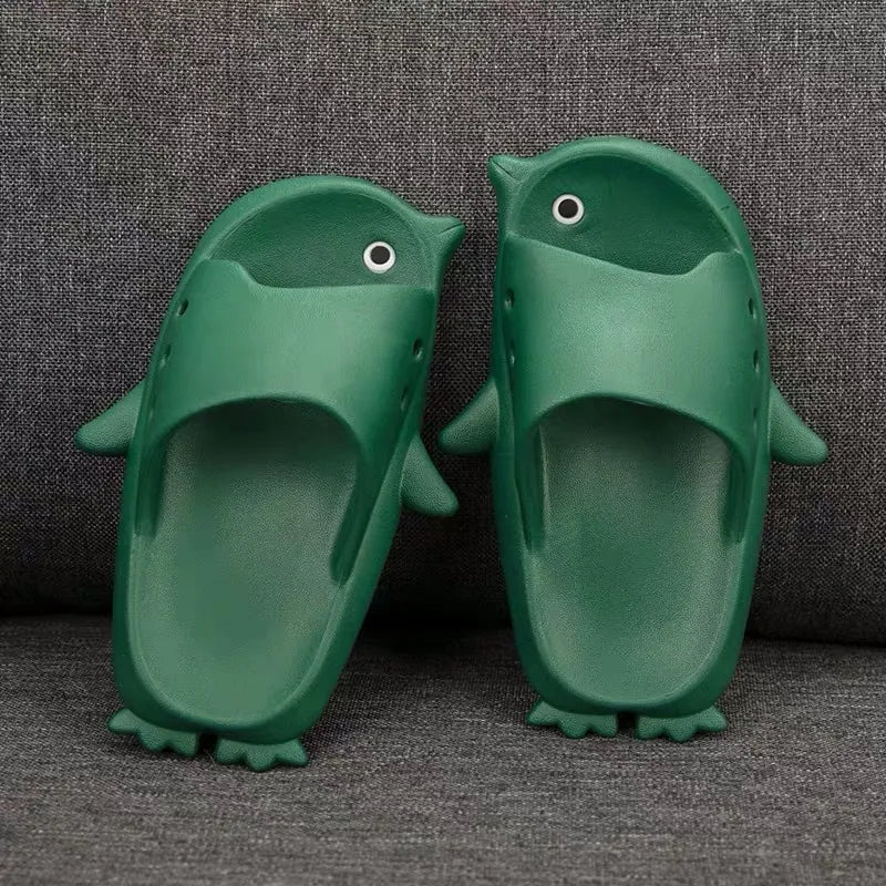 Green children's slippers shaped like penguins on a gray textured background