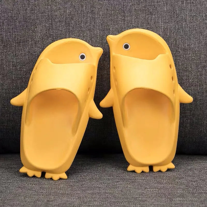 Pair of yellow penguin-shaped slippers on a dark textured background