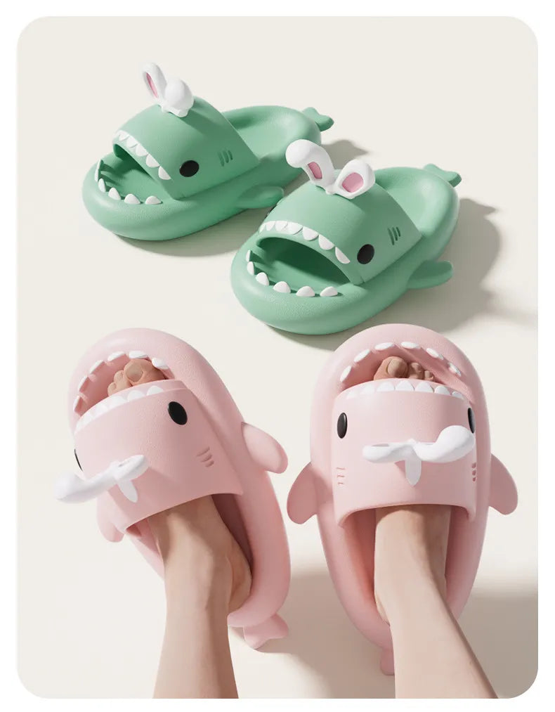Pair of shark-shaped slippers in green and pink on a light background